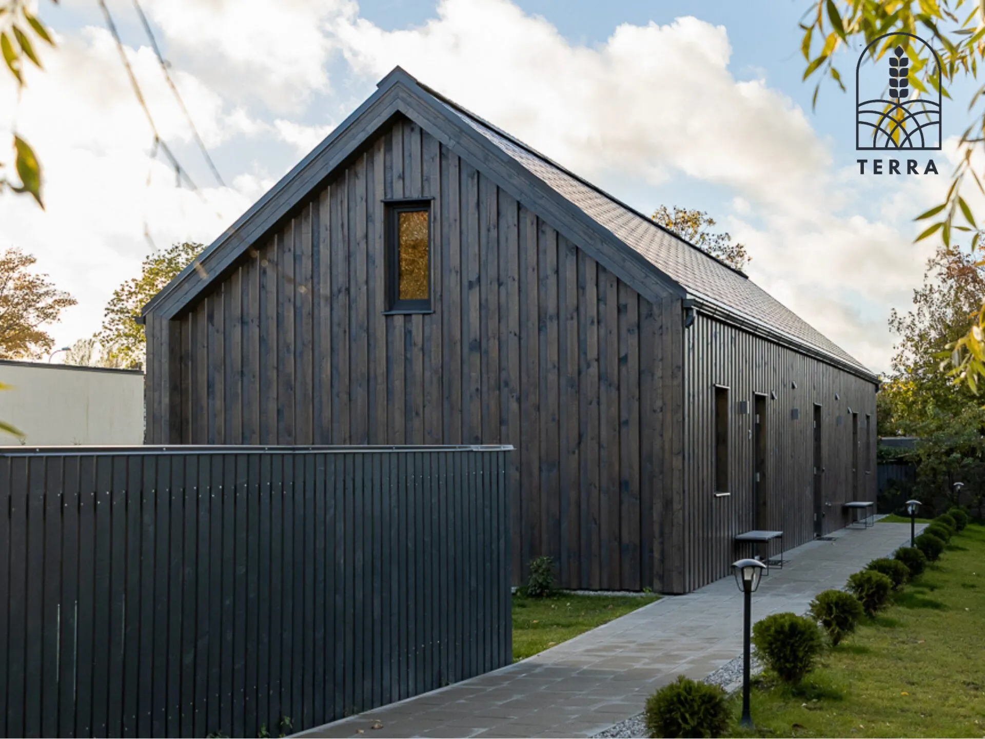 Terra House, a long dark timber house with a steep roof in Ventspils